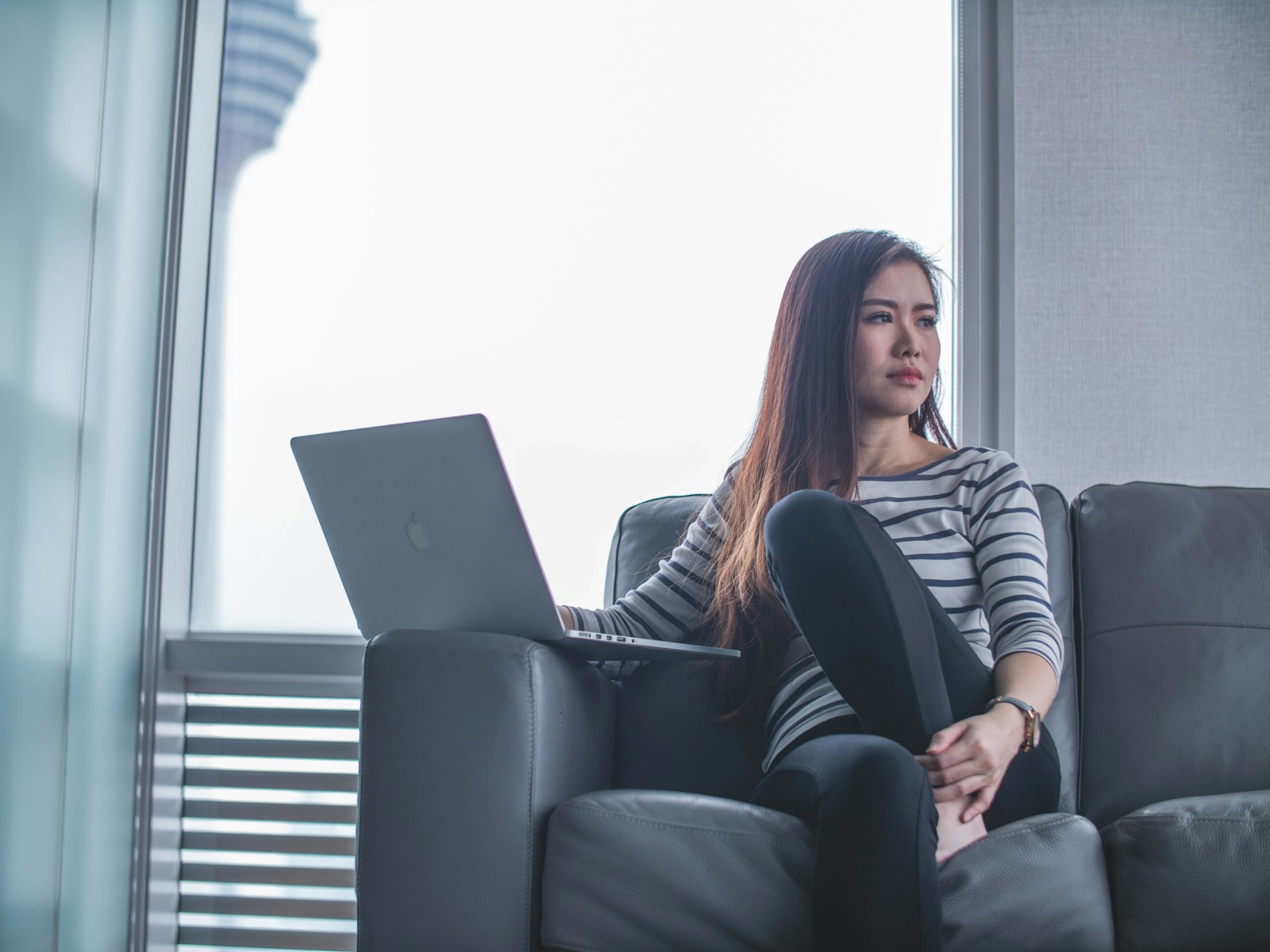 woman sitting on couch while using laptop computer, wondering why her homeowners rate increased